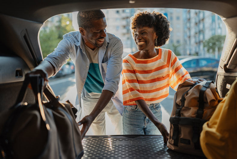 Couple loading luggage into the back of a car before a trip