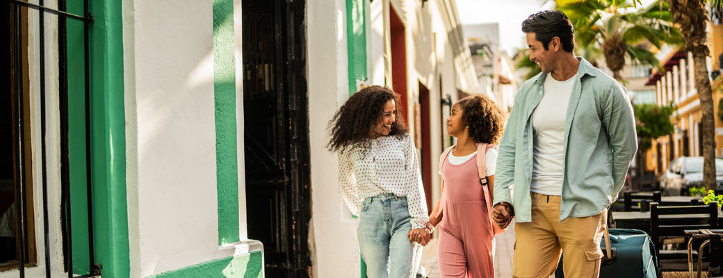 Family walking hand in hand along a city street while traveling