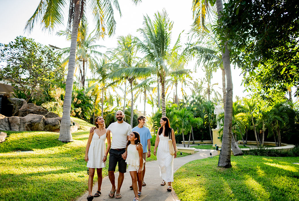 Family walking together along a palm-lined path