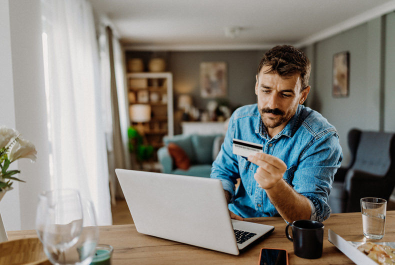 Man reviewing travel expenses on his phone while holding a credit card