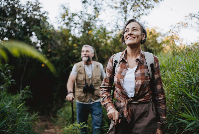 Two travelers with backpacks hiking on a wooded trail