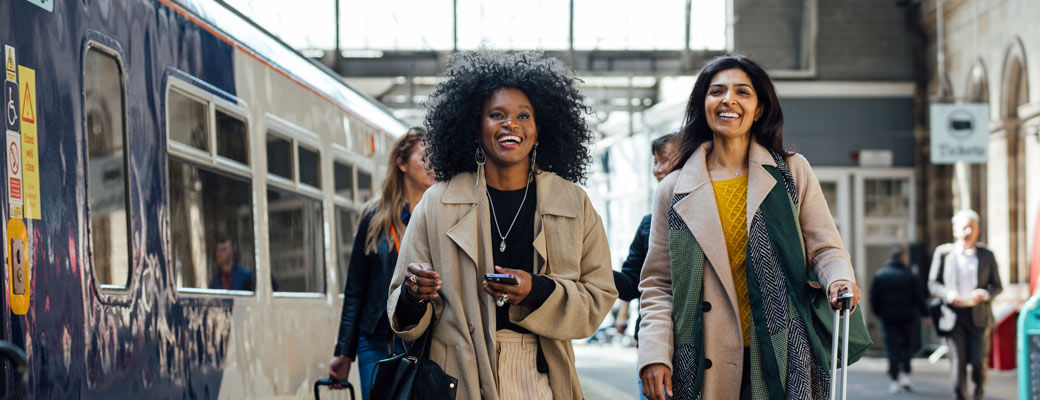 Two women navigating a busy train station with luggage